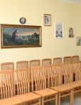 Wnętrze domu pomocy. Kaplica. Dwa rzędy krzeseł dla osób uczestniczących w mszach świętych. Na ścianie obrazy religijne